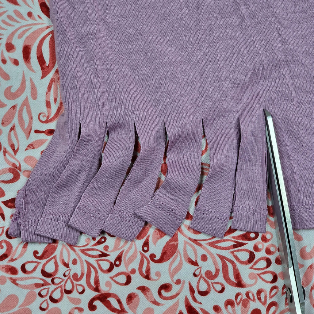 scissors cutting strips from the bottom of the t-shirt
